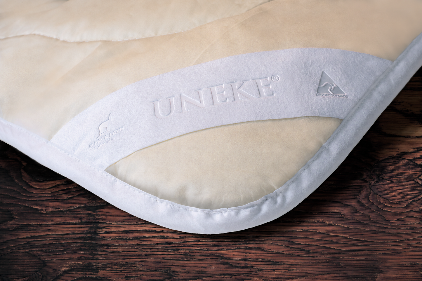 Close-up of a beige and white mattress pad with 'UNIKET' branding on a wooden surface.